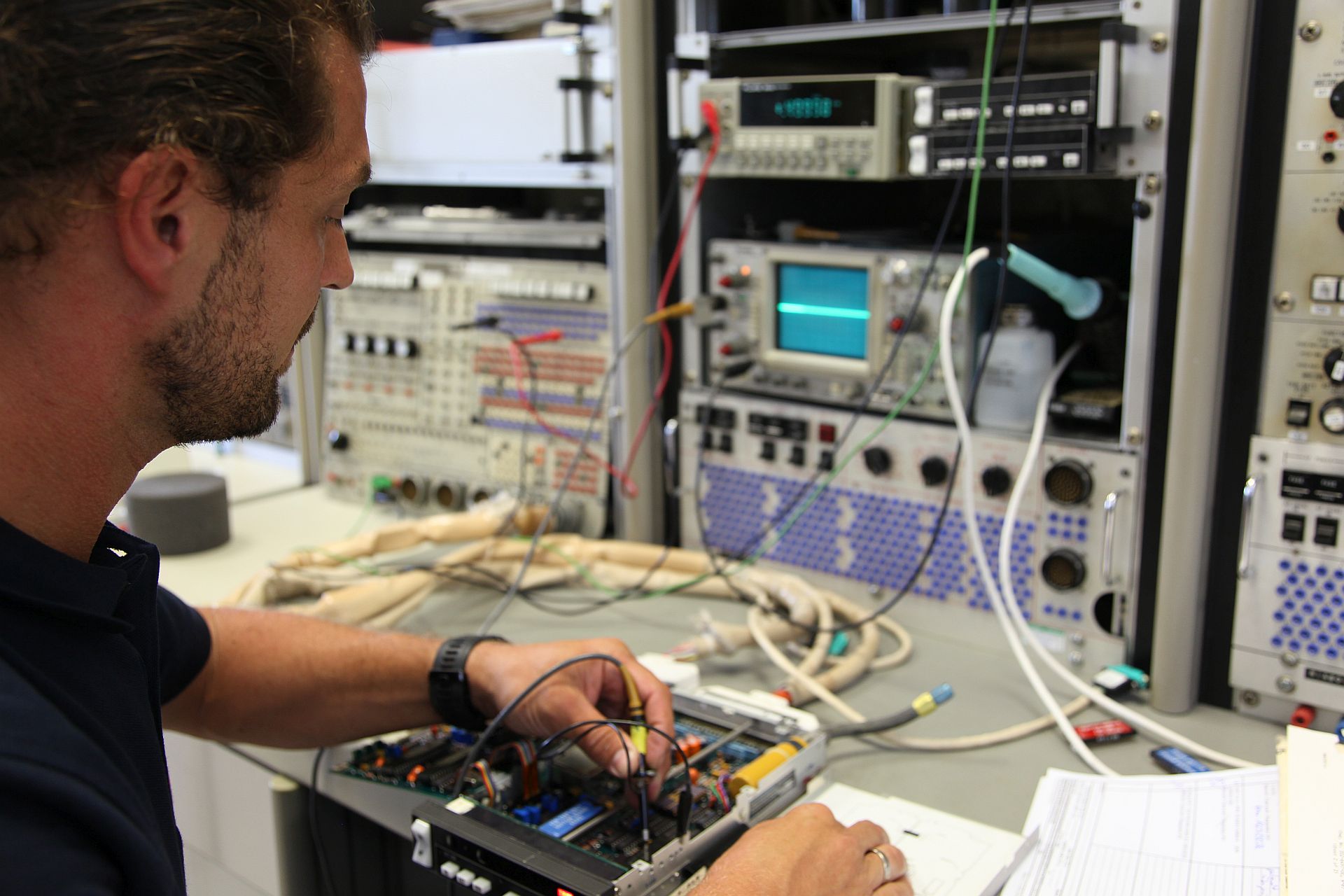 Techniker an seinem Arbeitsplatz bei der Überprüfung eines elektronischen Gerätes